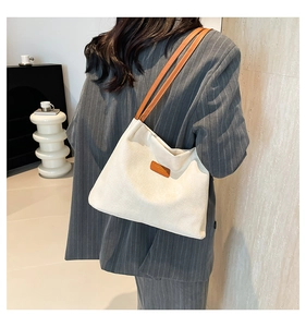 Close-up of off-white textured canvas tote bag with brown leather straps on a model