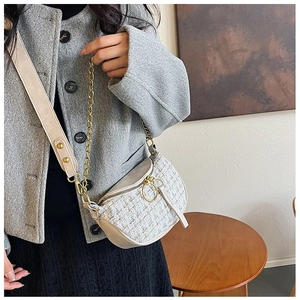Detail of tweed saddle bag showing woven texture, gold zipper, and chain shoulder strap