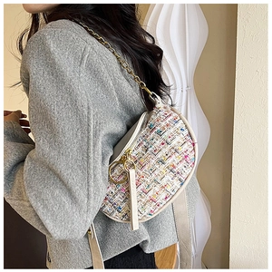 Close-up of multicolor tweed saddle bag with gold chain and cream leather trim detail