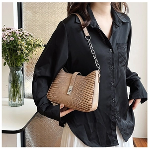 Detail of khaki crocodile pattern shoulder bag with a vintage metallic flip lock and chain strap