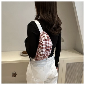 Close-up of red and white checkered crossbody bag with wide strap and triangular zipper
