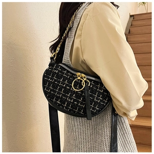 Detail of black tweed crossbody saddle bag with gold chain and large ring zipper pull