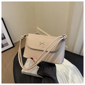 Détail du sac bandoulière beige avec boucle noeud argenté et bandoulière en corde fine