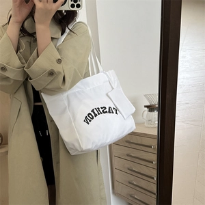 White canvas tote bag with fashion lettering and charm shown in a mirror selfie