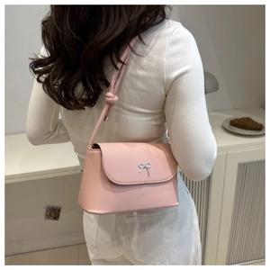 Détail d'un mini sac rose clair avec nœud argenté et bandoulière à nœuds décoratifs