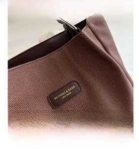 Macro shot of brown canvas tote bag texture with leather logo patch and metal ring detail