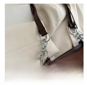 Detail of dark brown twill fabric tote bag with silver chain strap and leather finish
