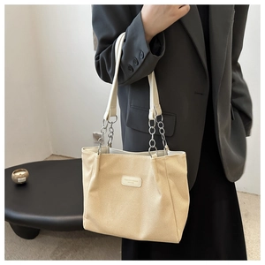 Dettaglio della borsa tote beige con patch in pelle e tracolla a catena in metallo
