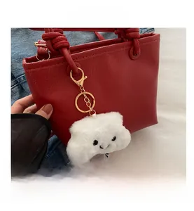 Dettaglio borsa rossa in pelle con ciondolo a nuvola e manico con nodo di design