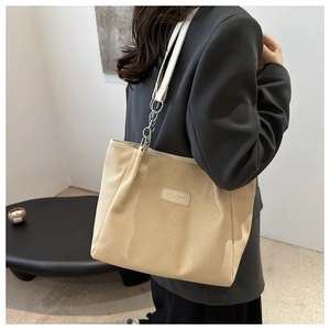 Detail of beige canvas tote with white leather and silver metal chain strap detail