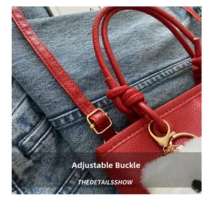 Dettaglio borsa in pelle rossa con fibbia dorata e tracolla regolabile
