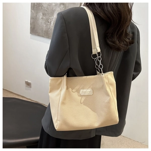 Detail of the textured off-white tote bag featuring leather and silver chain strap