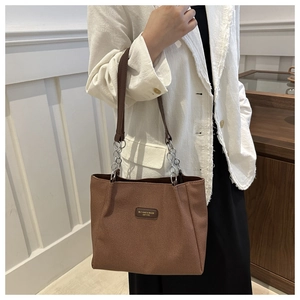 Dettaglio borsa tote in twill marrone con patch logo in pelle e tracolla a catena