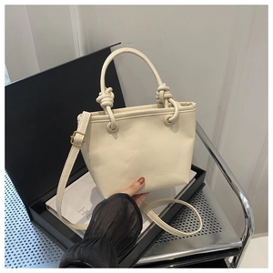 Close-up of beige lychee grain faux leather bucket bag with a stylish knotted handle design