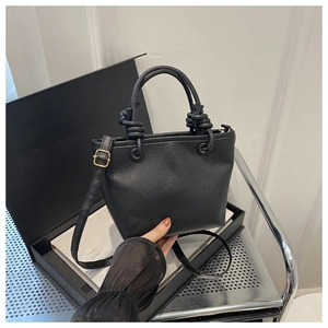 Detail of black lychee grain leather bucket bag featuring rope knot handle and gold hardware