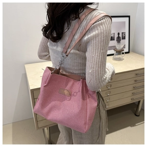 Detail view of pink corduroy tote bag with leather logo tag and chain strap on shoulder