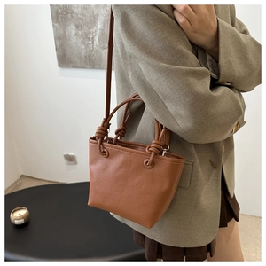 Close-up of caramel brown pebble leather bucket bag with knotted handle detail