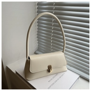 Macro detail of creamy white leather handbag with golden twist lock on a book