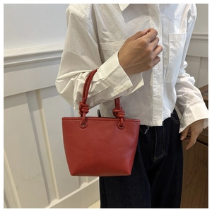 Detail of red leather bucket bag with elegant knotted handle and lychee texture