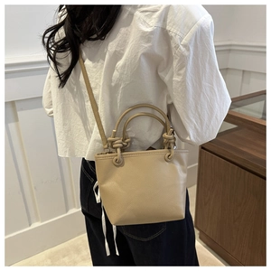 Detail view of khaki leather bucket bag featuring knot handle and pebble texture