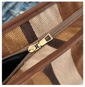 Detail of the golden metal zipper and striped fabric texture on this tote bag