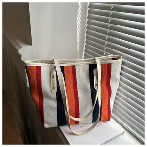 Close-up of striped canvas tote bag with leather handles on a bright sunny windowsill