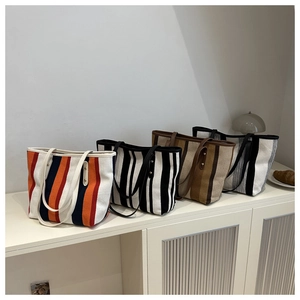 Detailed view of four large canvas tote bags with vertical stripes in various colorways