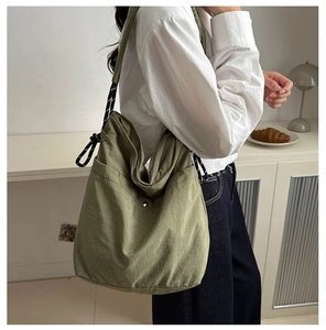 Detailed side view of green canvas tote bag with decorative rope strap in home setting