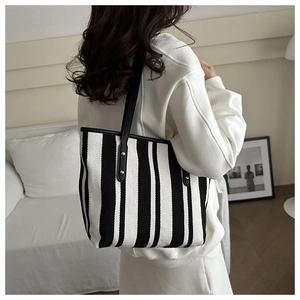 Detailed close-up of large striped tote bag with leather straps and gold metal rivets