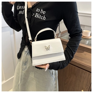 Detailed shot of white leather mini crossbody bag with butterfly metal hardware detail