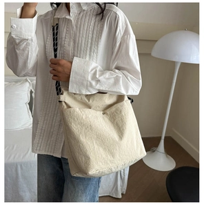 Detail of off-white canvas tote bag with large double front pockets and woven rope strap