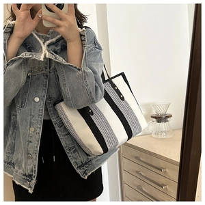 French style striped canvas tote bag with black leather straps in a home setting