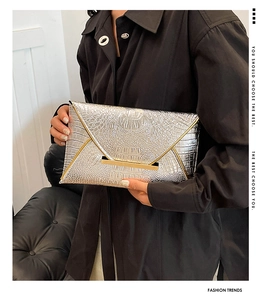 Silver envelope clutch bag with crocodile texture and gold metal frame shown on a model