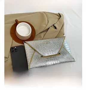 Silver crocodile pattern envelope clutch showing size comparison with a smartphone