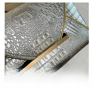 Detailed macro view of silver croc-textured leather with golden V-shaped metal clasp