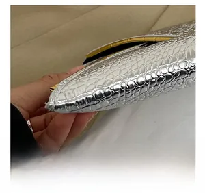 Close-up of precise stitching and silver crocodile embossed texture on luxury handbag