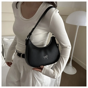 Gros plan d'un sac hobo noir en demi-lune avec nœud argenté et bandoulière réglable