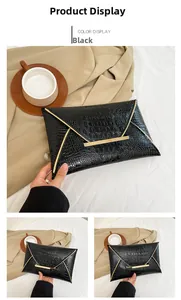 Close-up of black crocodile-textured envelope clutch bag with gold metal accents on fabric