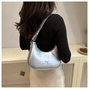 Detail of silver crescent moon bag featuring a delicate metal bow clasp and sleek finish