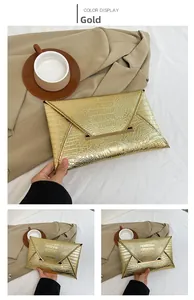 Detailed view of a shiny gold crocodile texture envelope clutch bag with metal buckle