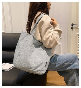 Detail der graublauen Nylon-Tragetasche mit Modeetikett in einer Lifestyle-Umgebung