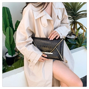 Detail of black crocodile texture clutch with gold metallic V-trim and magnetic closure