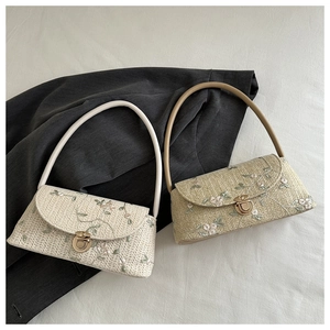 Detail of woven straw shoulder bags with delicate floral embroidery and metal clasps