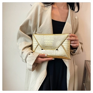Close-up of golden crocodile pattern envelope clutch bag with metallic glossy finish