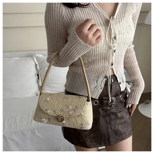 Close-up of woven straw bag featuring delicate floral embroidery and vintage metal clasp