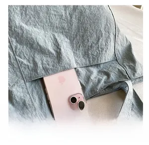 Détail de la poche latérale d'un sac cabas texturé contenant un smartphone