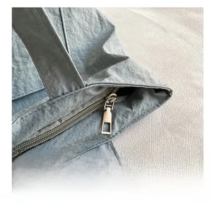 Détail de la fermeture éclair dorée et du nylon texturé sur le sac fourre-tout gris