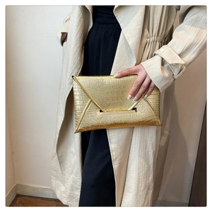 Detail of a gold crocodile embossed envelope clutch bag with metallic frame accent