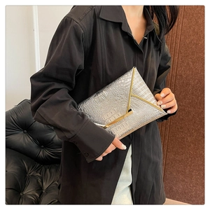 Detail of silver crocodile pattern envelope clutch featuring a V-shaped golden metal trim