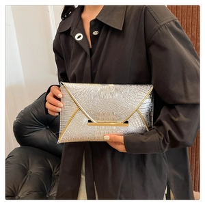 Detail of silver crocodile pattern envelope clutch bag with metallic gold trim and texture